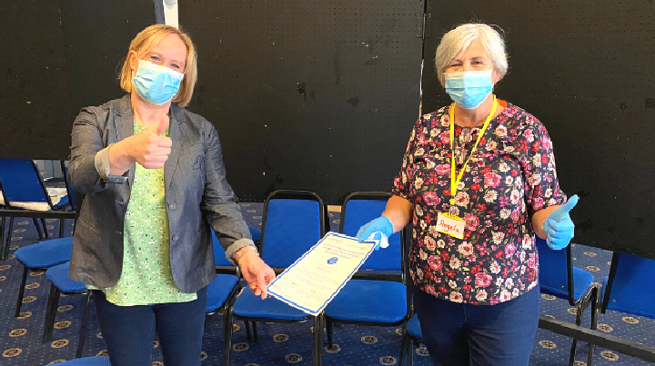 Alison Welsh, former Centre Manager for mass vaccination sites in South Sefton, presents a certificate to volunteer Angela Darby