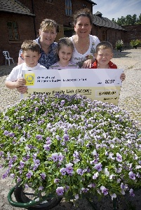 Key worker at Knowsley Family Link Lynn Hudson and Sam Armstrong and (front row l to r) Lynn’s son Joseph (10) nine-year-old Sarah Lawler who is helped by the charity, and Lynn’s son Lewis (9) receive the cheque at the National Wild flower Centre in Liverpool.