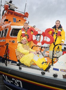RNLI volunteer lifeboat crew members Rob Archer (seated), Mark Barker (left) and Ian Anderson limber up for the SOS Day rowathon. (Credit RNLI/Tom Collins)