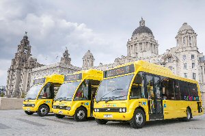 three of the new hybrid buses in front of the Three Graces at the Pier Head, Liverpool