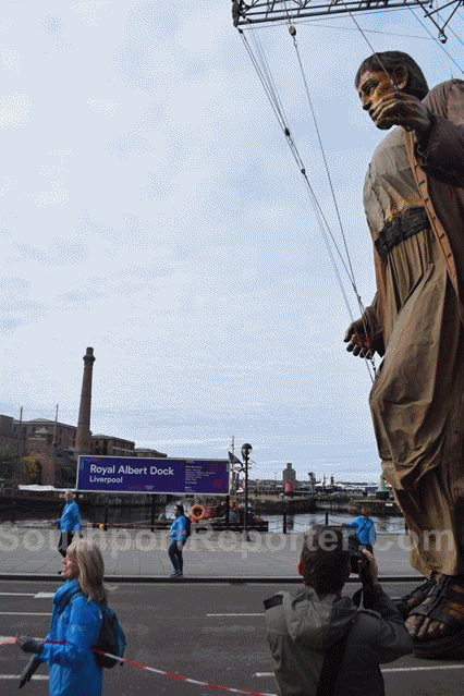 Giant walks past the Royal Albert Dock, Liverpool, UK