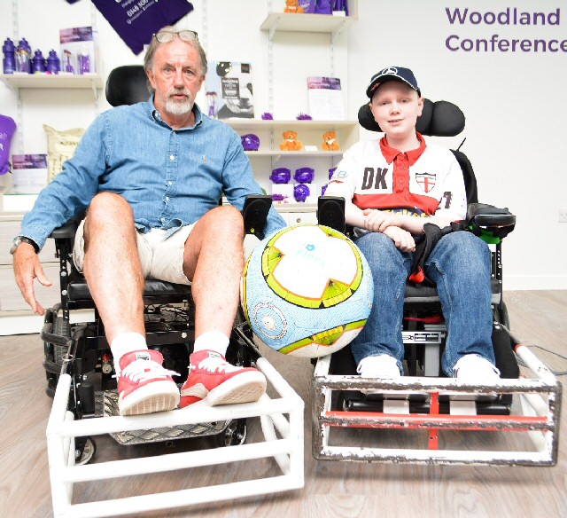Photo caption: Mark Lawrenson tries out a football powerchair for size alongside Caudwelll Children benificiary Dylan Kelsal
