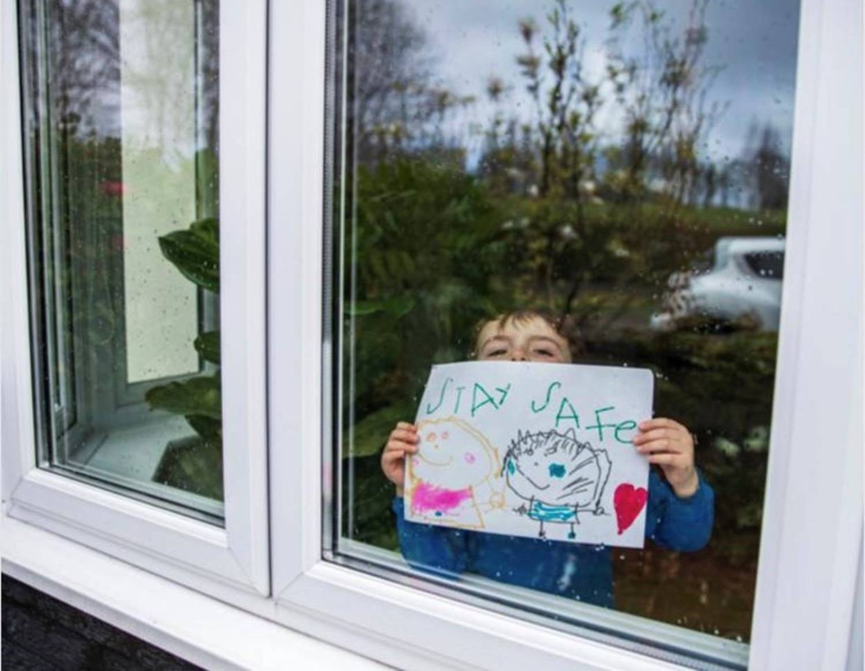 Young resident Fox Capper holds up a drawing urging people to stay safe during the Pandemic.